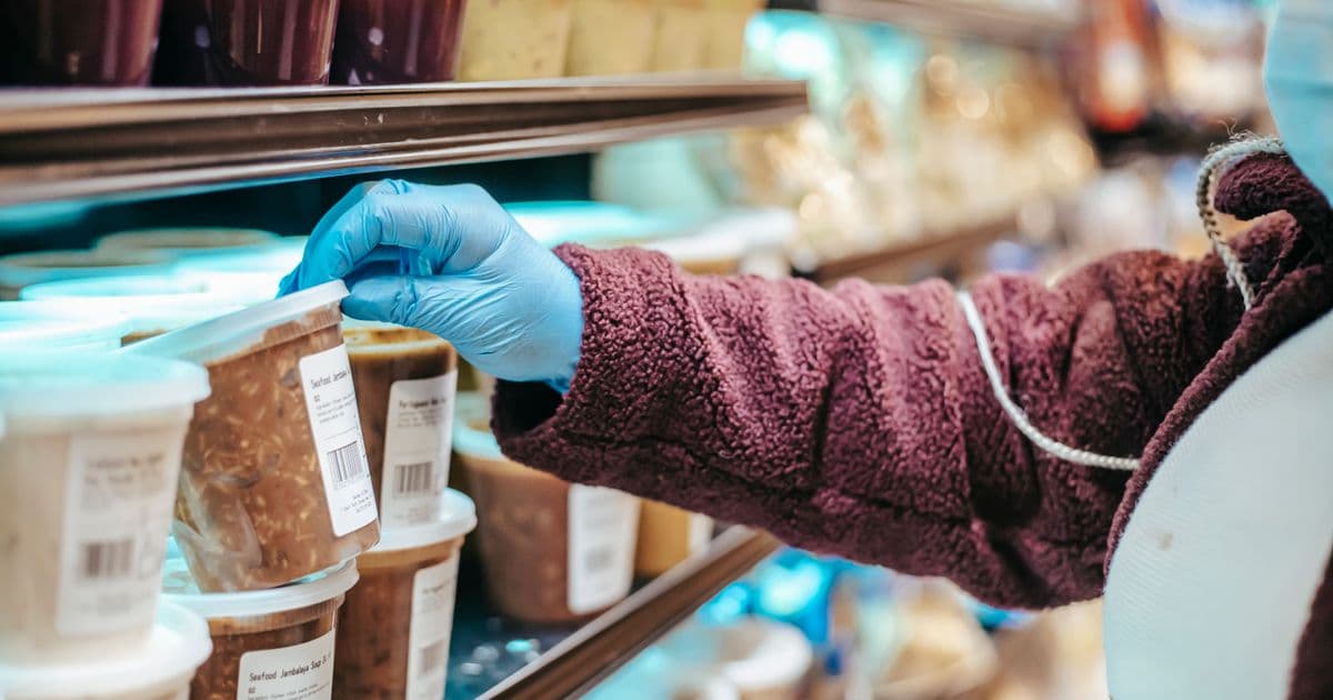 Person reading a nutrition label on a food package, highlighting serving size, %Daily Value, and added sugars